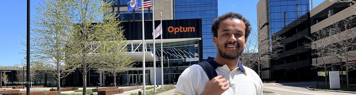 Robera Legese stands on the Optum campus with the company logo showing on the building entrance in the background